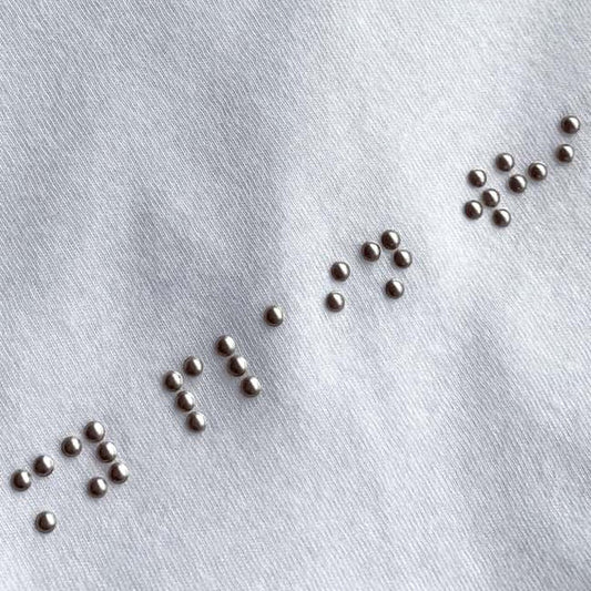 A white t-shirt with braille made from beads