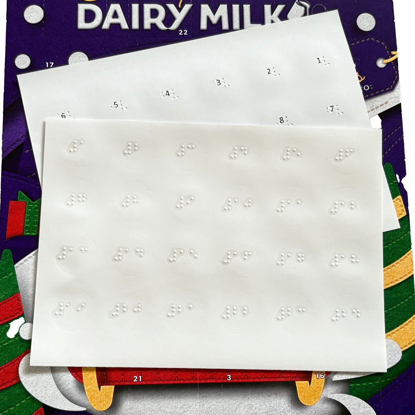 Braille advent calendar labels sat on top of a Dairy Milk advent calendar.