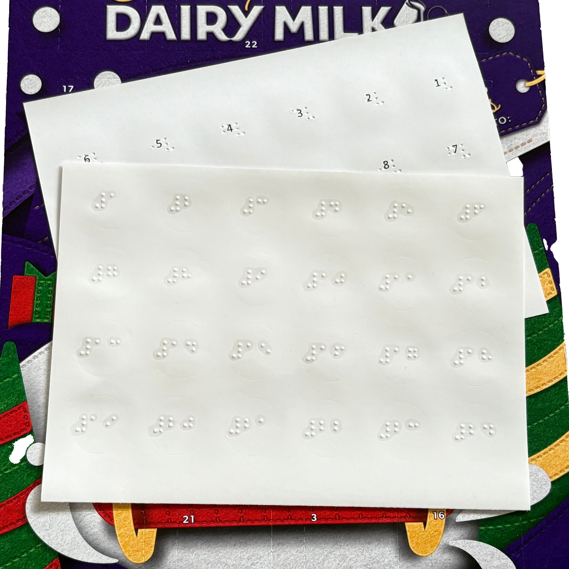 Braille advent calendar labels sat on top of a Dairy Milk advent calendar.