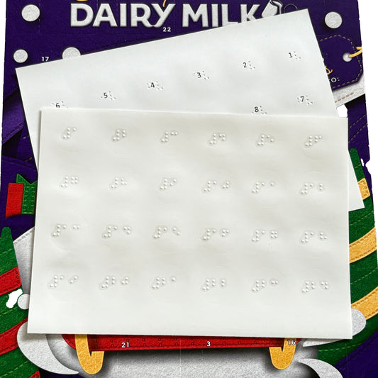Braille advent calendar labels sat on top of a Dairy Milk advent calendar.