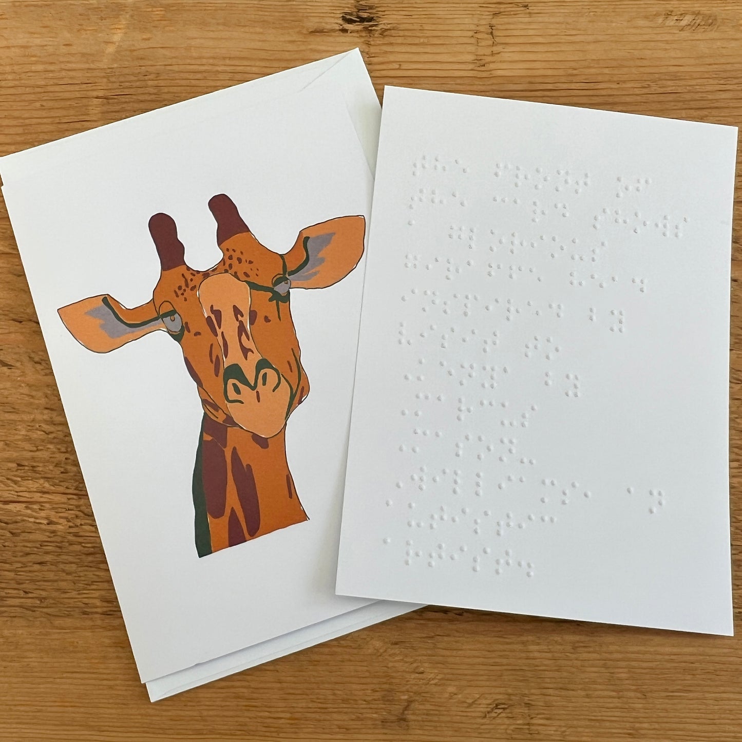 Greetings card featuring a giraffe illustration with a separate white insert embossed with Braille