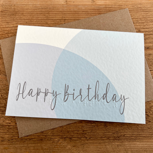 Birthday card with 'Happy Birthday' text and abstract pastel circles, featuring Braille underneath.