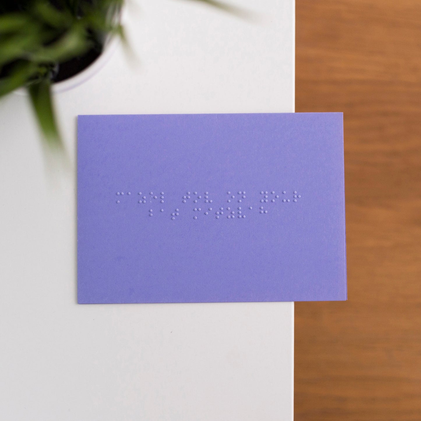 A vibrant purple card lay flat on a table with mazel tov on your bat mitzvah written in lower case grade one braille.