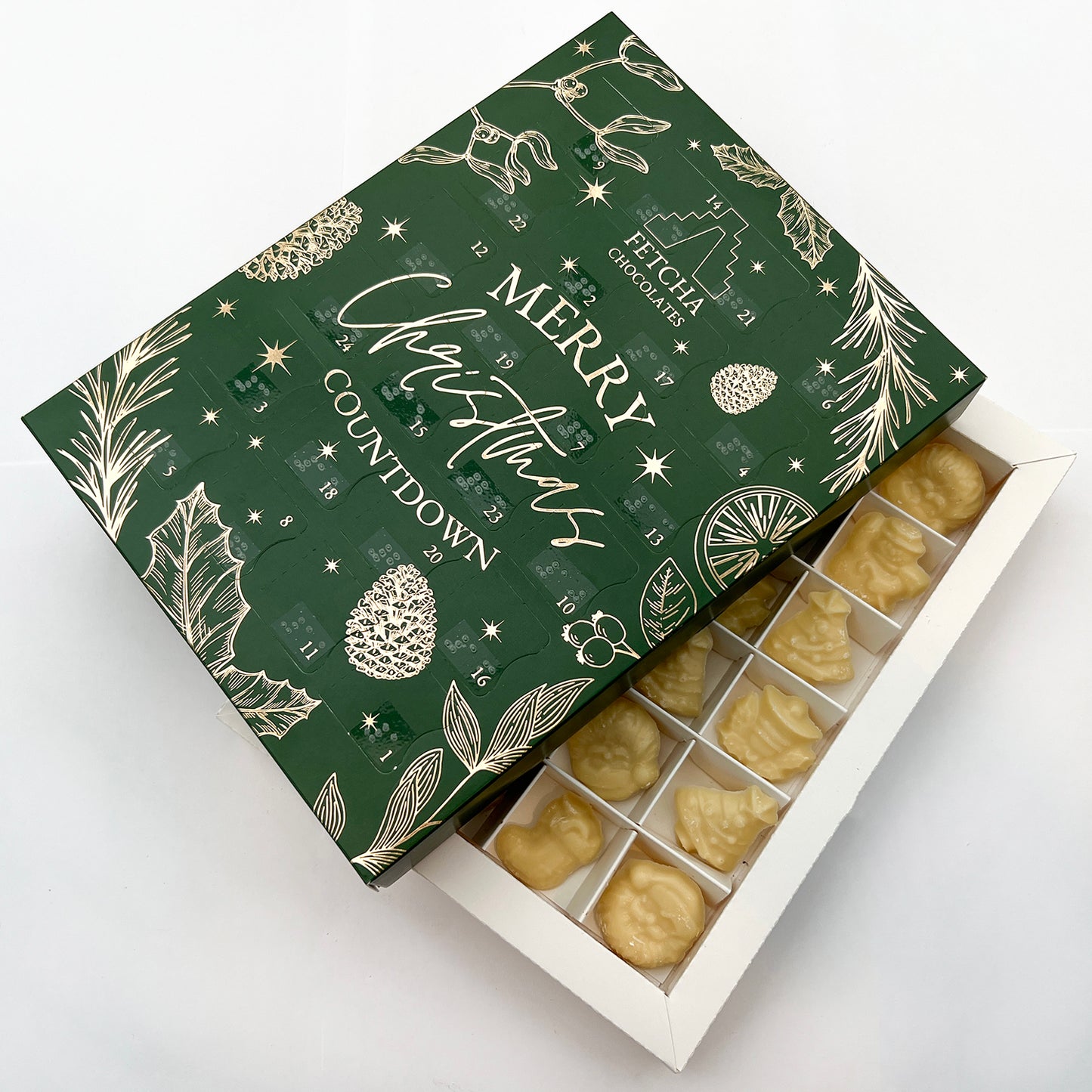 A shot of the inside of the advent calendar, showing multiple pieces of white chocolate. The green advent calendar box is sat on top, at an angle.