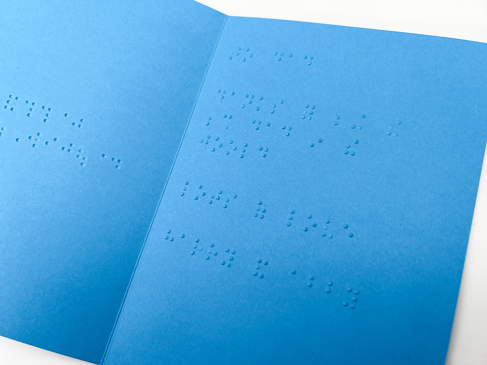 An open blue card with a braille message inside.
