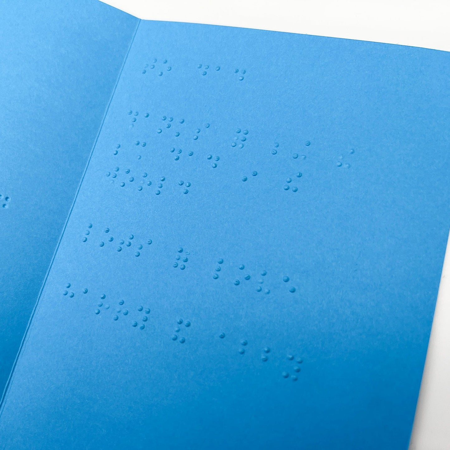 An open blue Father's Day card with text inside that reads to dad, thanks for being the best dad in the world, lots of love harry and abby, in lower case grade 2 UEB braille.