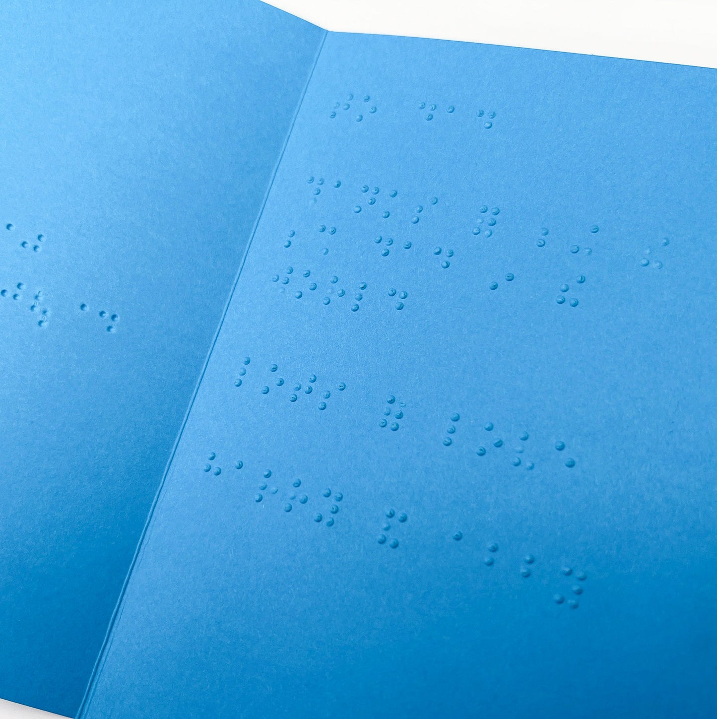An open blue card with a braille message inside.