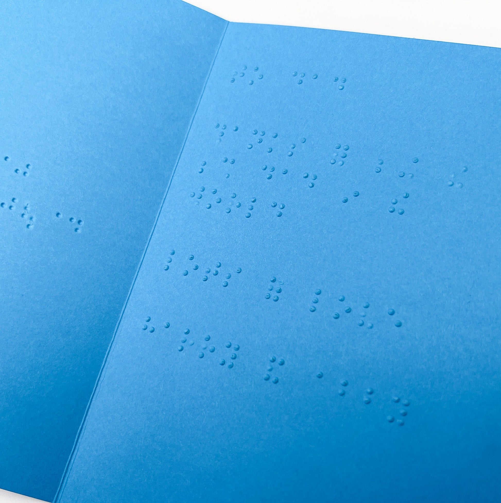An open blue card with a braille message inside.