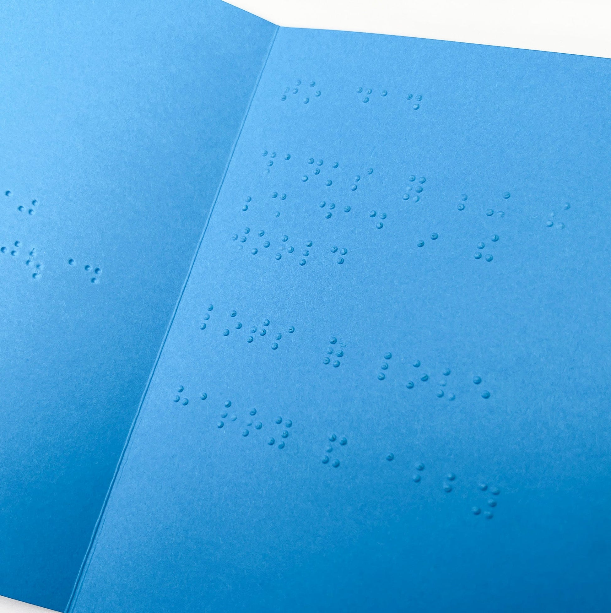 An open blue card with a braille message inside.