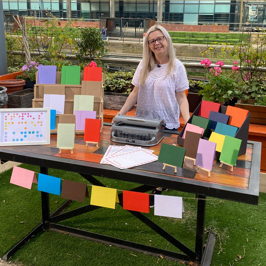 Hayley Kellard, founder of Dotty About Braille stood behind her market stall on Steph's Packed Lunch. There are lots of colourful braille cards and a Perkins brailler.