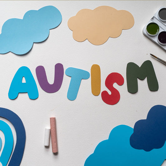 The word autism written out in colourful cut out letters with colourful cut out clouds around it