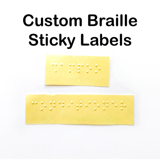 A white box with text across the top saying Custom Braille Sticky Labels, there are two yellow backed braille labels in the middle saying shampoo and conditioner.