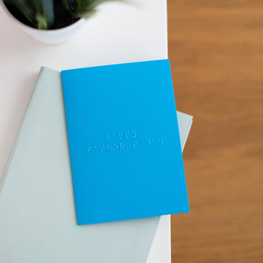 A vibrant blue greetings card with happy father's day written in lower case braille.