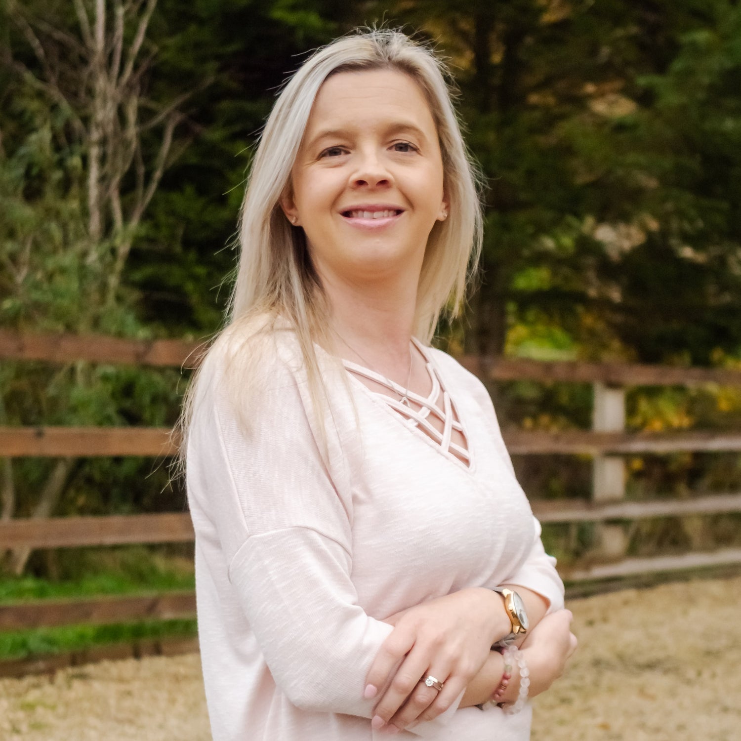 Hayley Kellard, a white, blonde female wearing a pink jumper, she's stood with her arms folded and is smiling towards the camera.