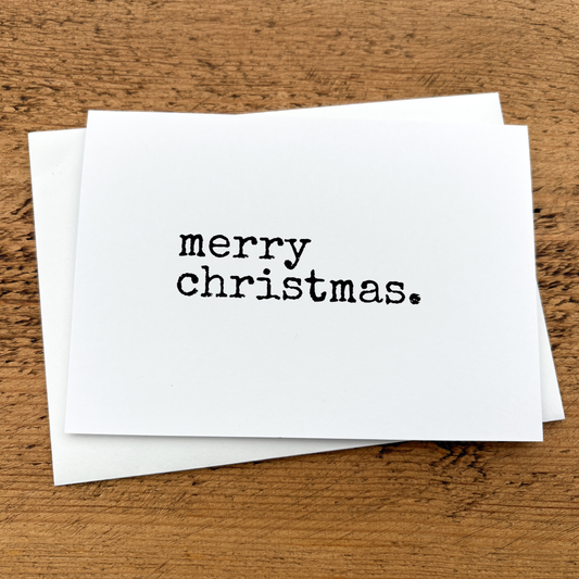 A white A6 card with Merry Christmas written in black typewriter style font.