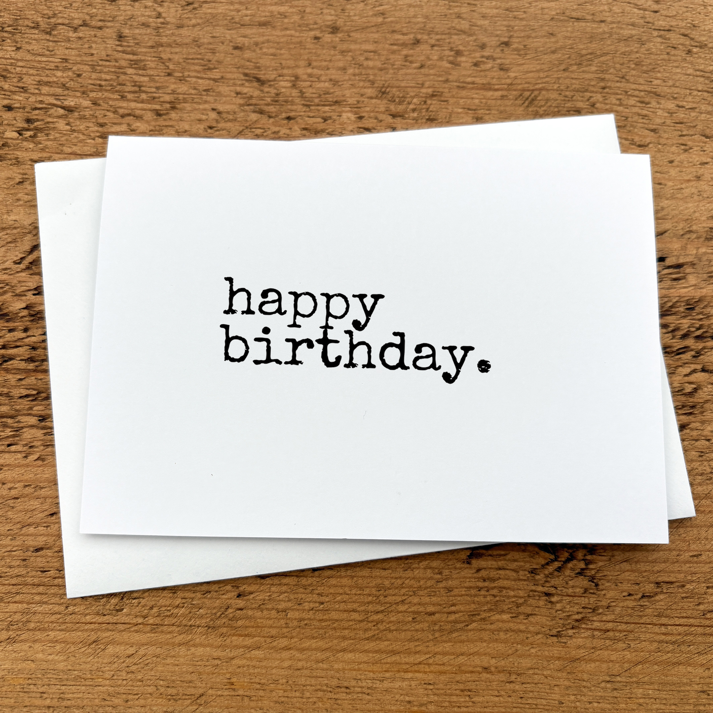 A white A6 card with text that reads: happy birthday written in black typewriter style font.