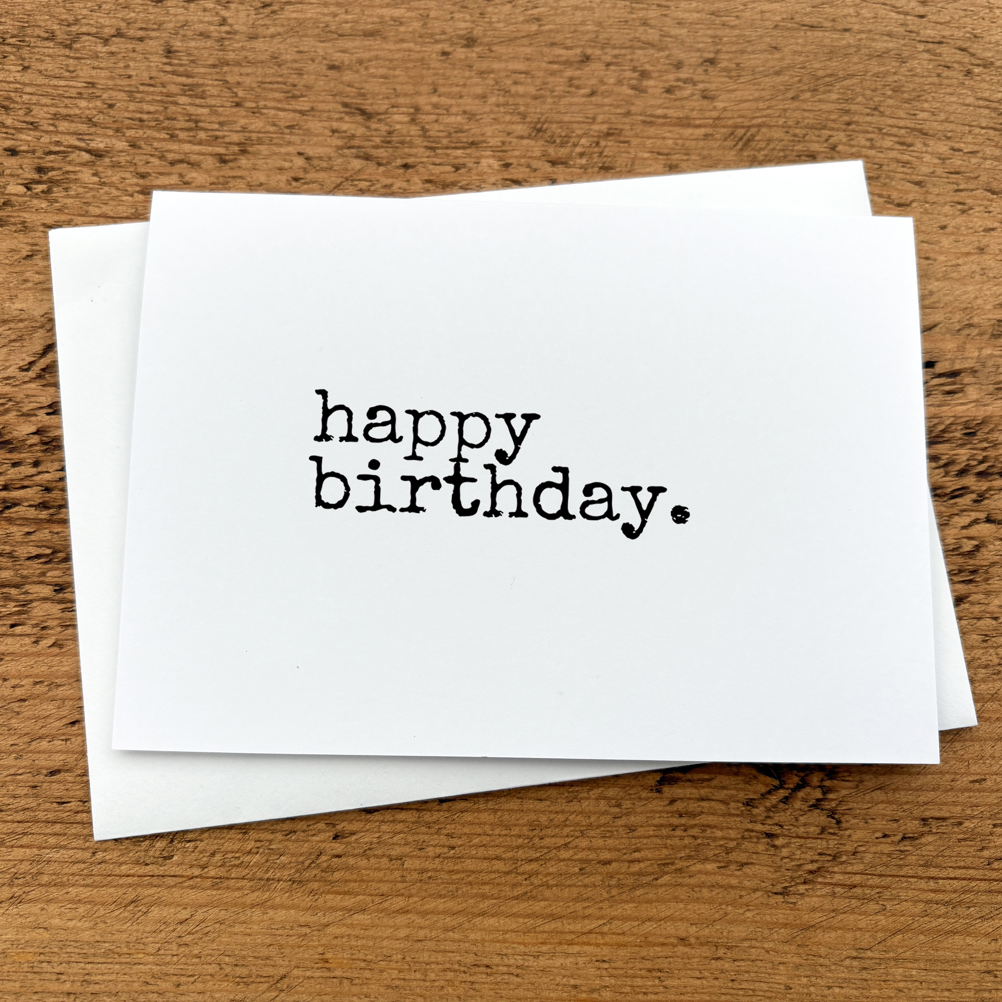 A white A6 card with text that reads: happy birthday written in black typewriter style font.