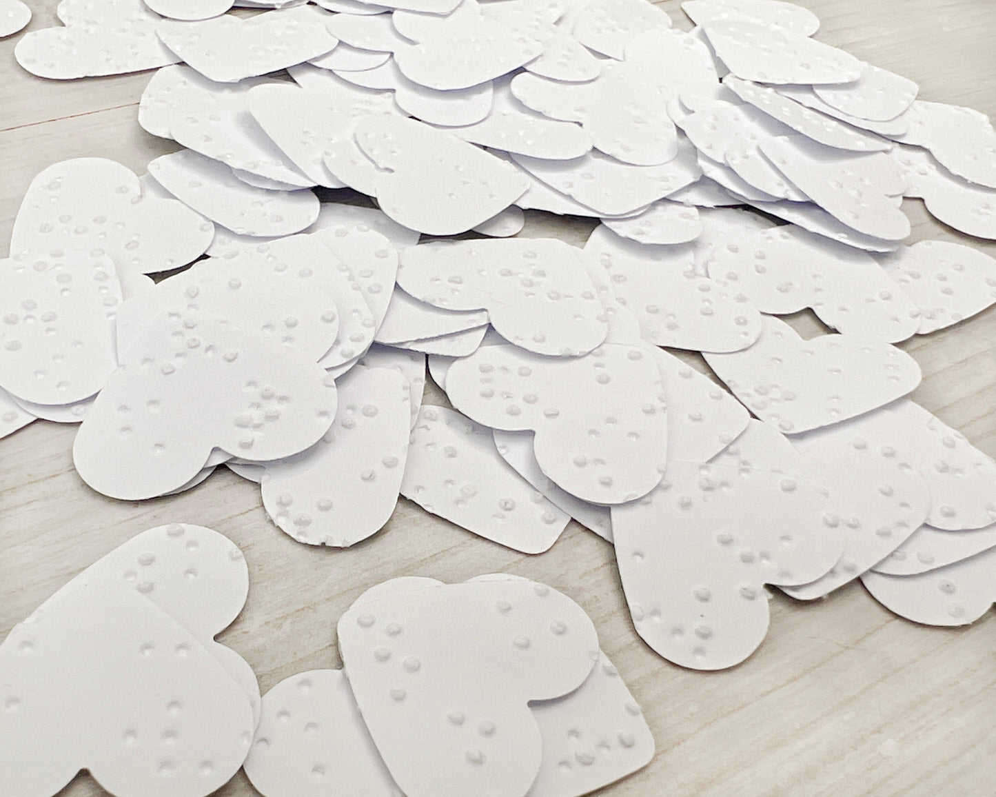 2.5cm hearts cut from white braille paper.