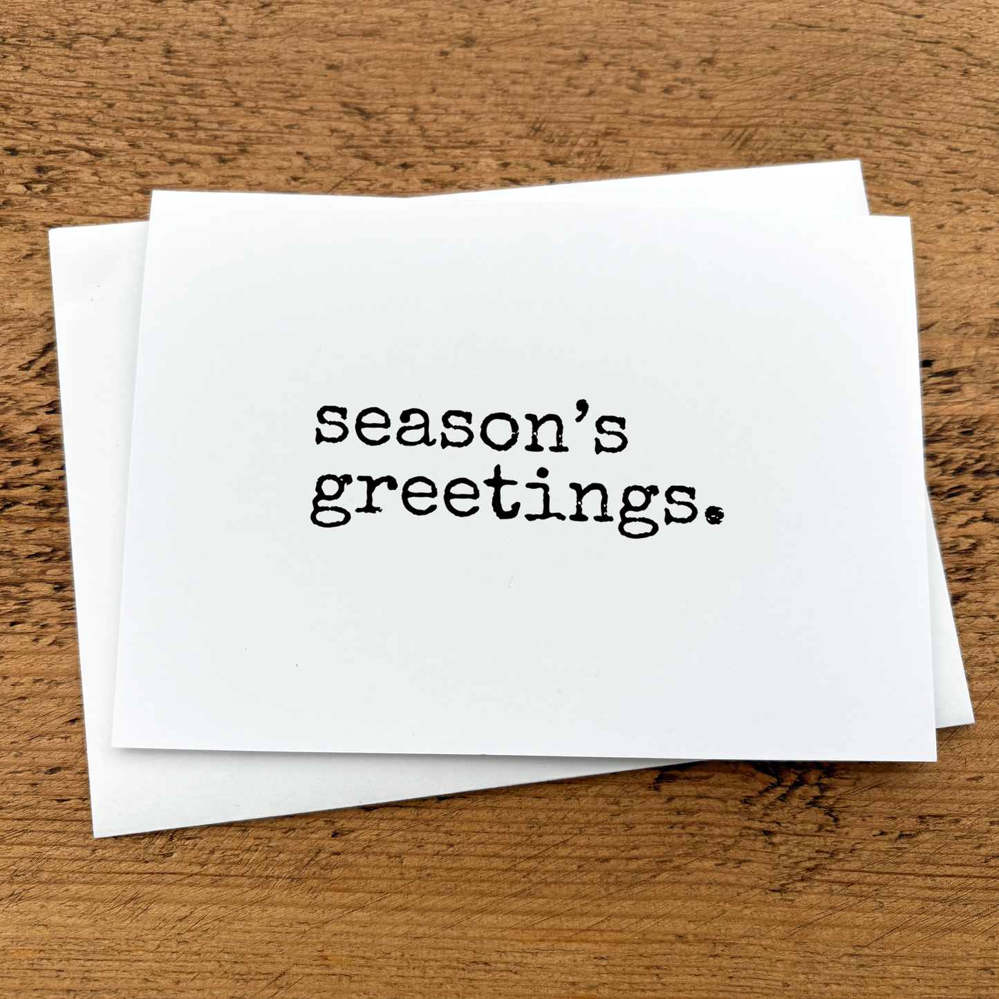 A white A6 card with Season's Greetings written in black typewriter style font.