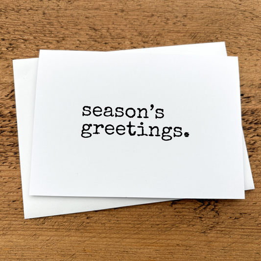 A white A6 card with Season's Greetings written in black typewriter style font.