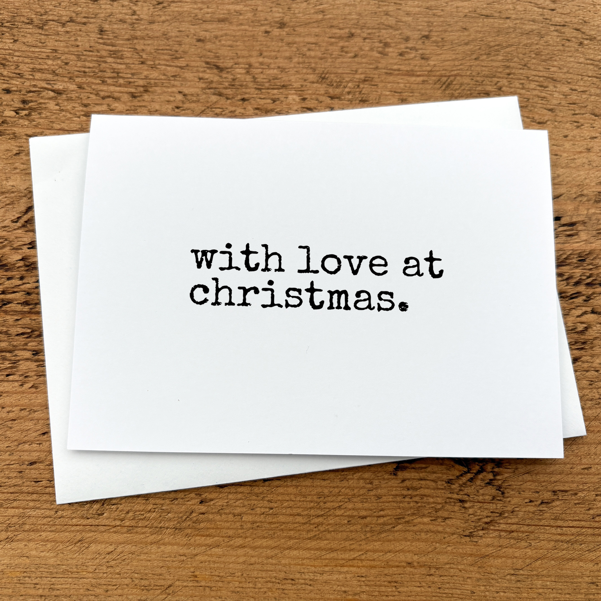 A white A6 card with text that reads: with love at Christmas written in black typewriter style font.