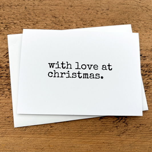 A white A6 card with text that reads: with love at Christmas written in black typewriter style font.