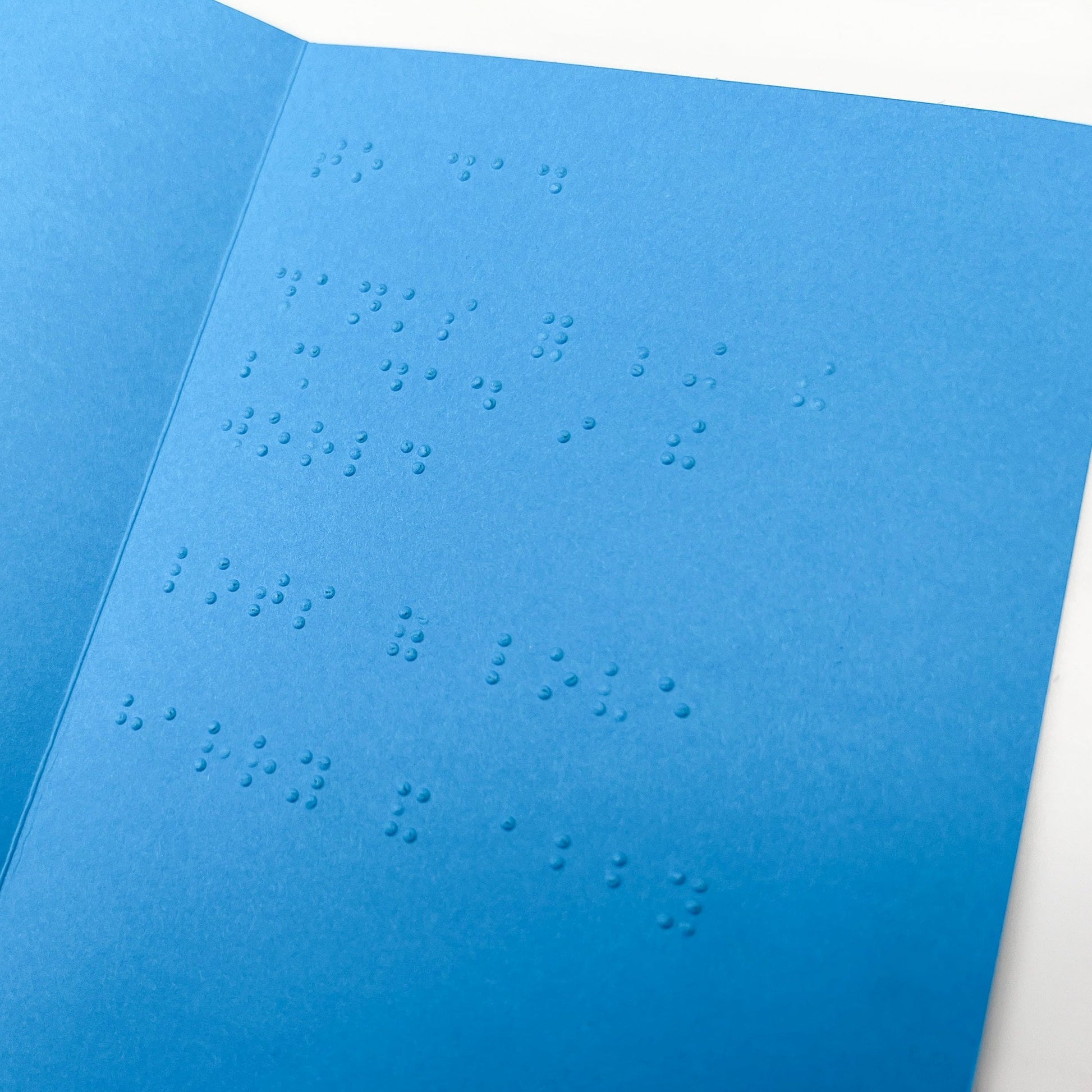 An open blue card with a braille message inside.