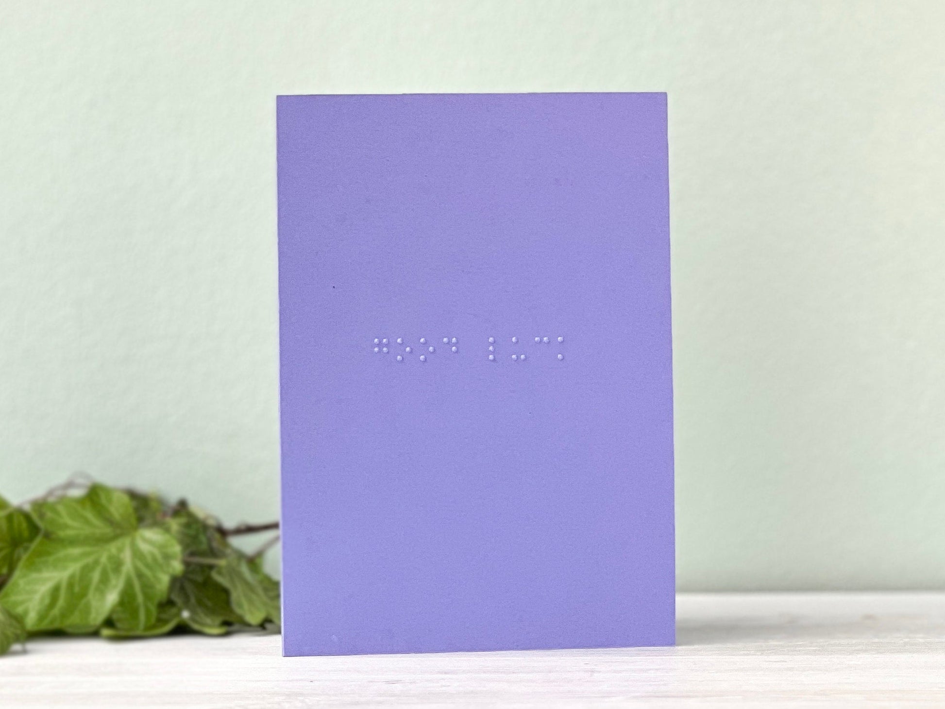 A portrait vibrant card with good luck written in grade 1 braille.