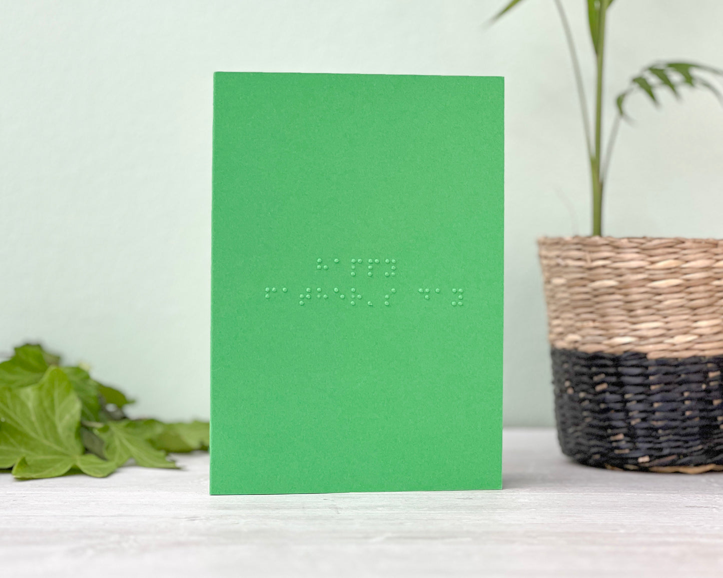 A vibrant green landscape greetings card with happy father&#39;s day written in grade 1 lower case braille.