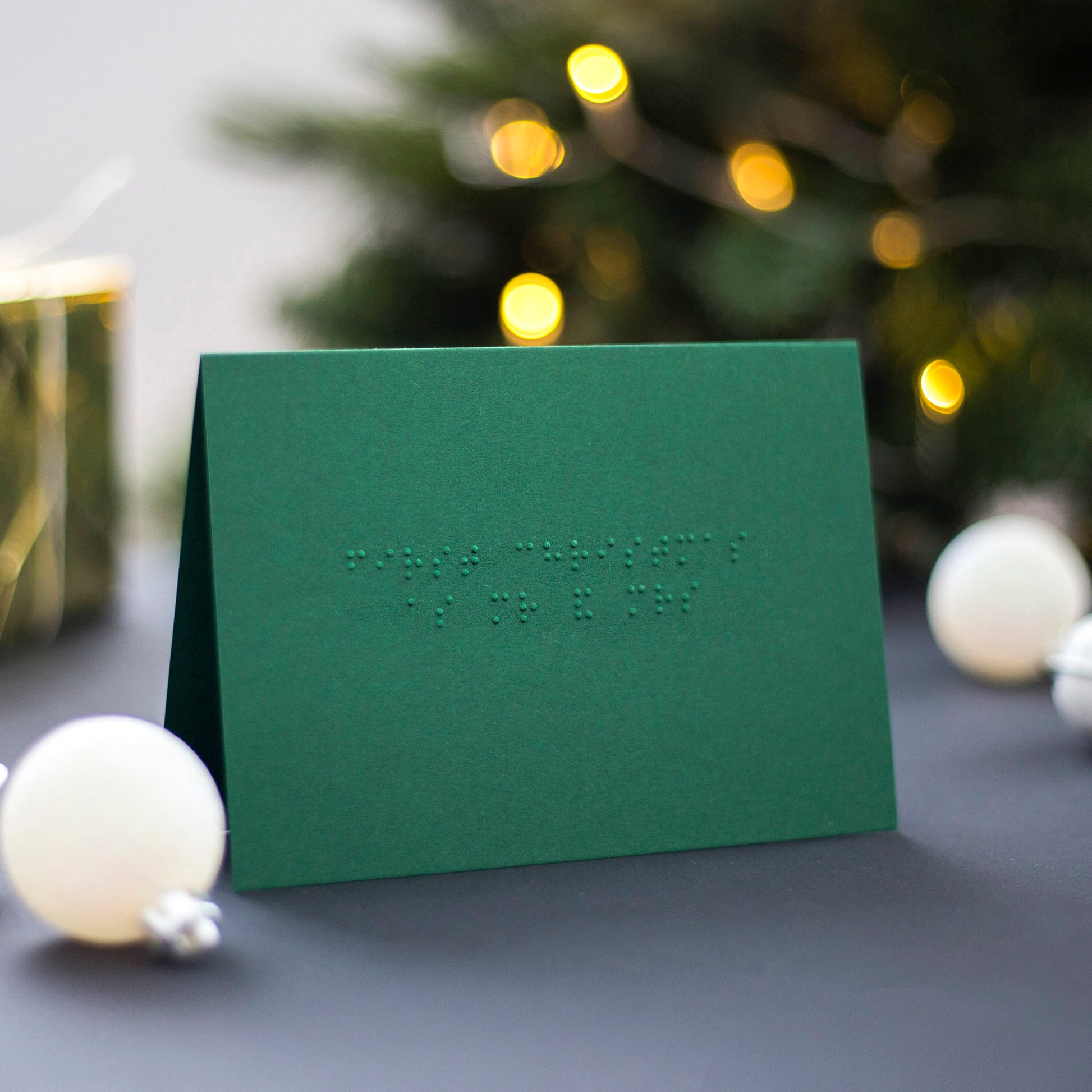 A Christmas green braille Christmas card with First Christmas as Mr & Mrs written in lower case UEB.