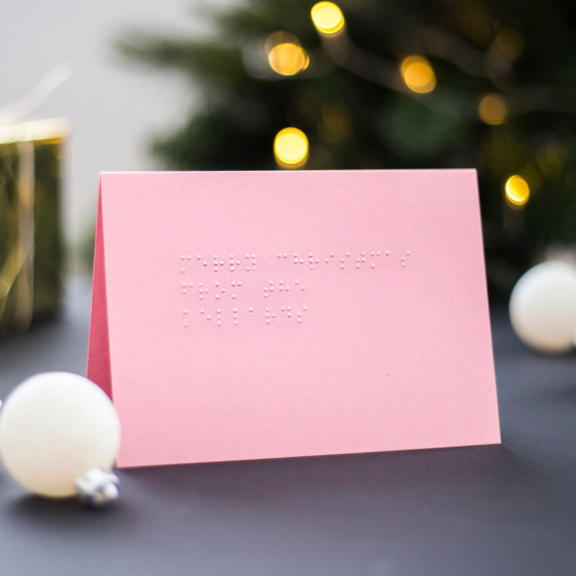 A pink braille Christmas card with Merry Christmas from the Kellards written in lower case UEB.