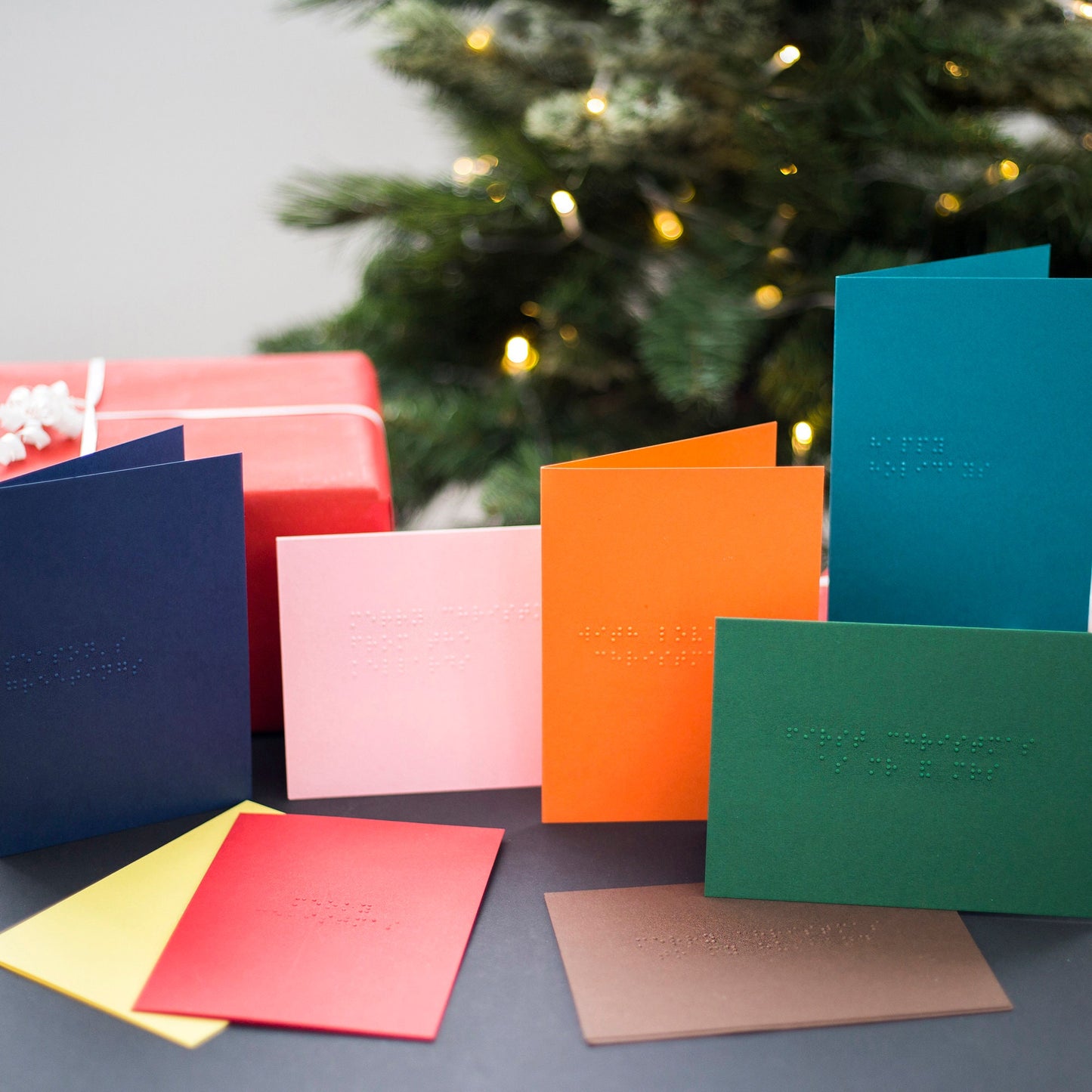 Braille Christmas cards in eight colours including red, green, pink, yellow, orange, teal, navy and chocolate.