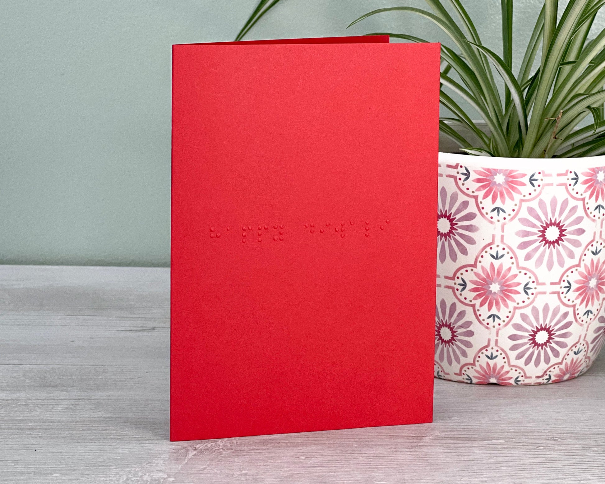 A vibrant red card with happy diwali in lower case unified English braille.