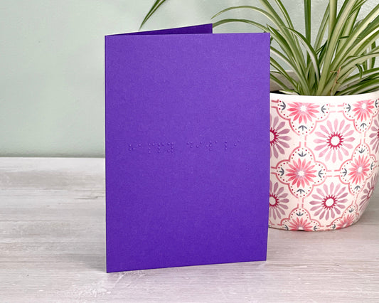 A vibrant purple card with happy diwali in lower case unified English braille.